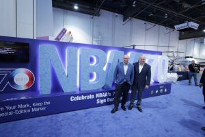 Astronauts Mark and Scott Kelly with NBAA 70th anniversary sign at NBAA17