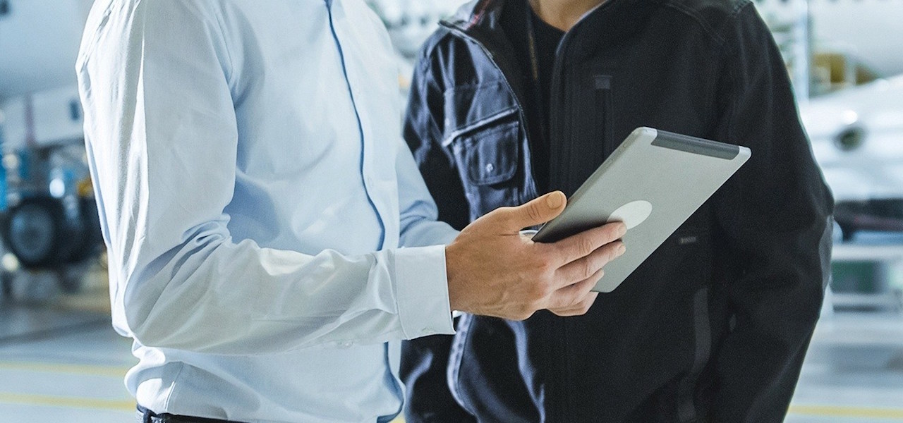 aviation management - two men using ipad in hangar